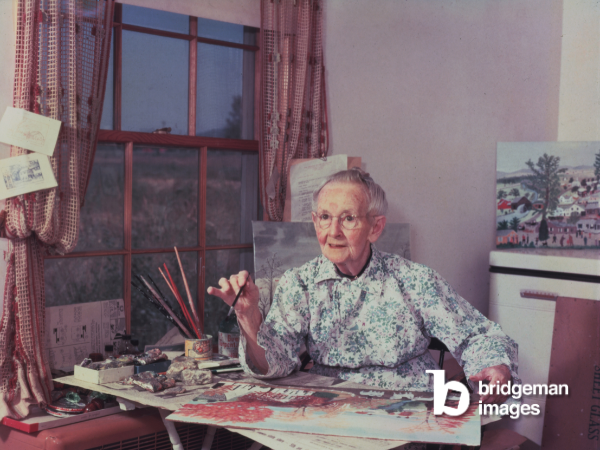 An image of Grandma Moses paitning in her room in 1952