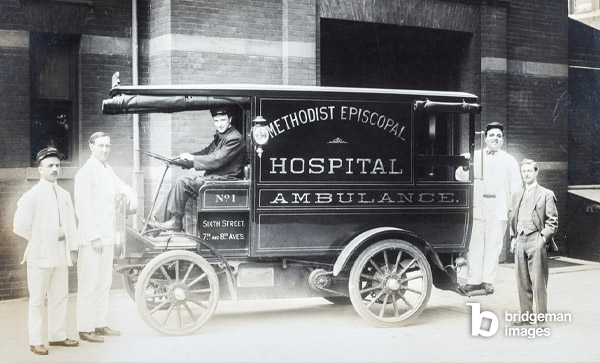 Quatre assistants et un médecin posent devant une ambulance à moteur de l’hôpital épiscopale méthodiste