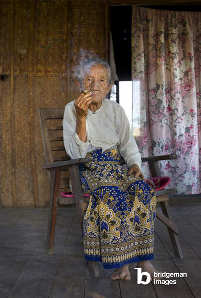 Portrait inside her home of an elderly Burmese woman with cigar and traditional clothing. Small floating village near Nyaungshwe, Shan State, Myanmar 2014 (photo) / Private Collection / © Salvo Galano. All rights reserved 2022 / Bridgeman Images