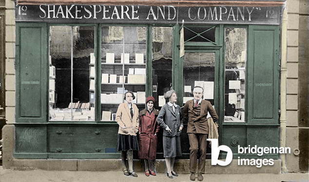 Ernest Hemingway and Sylvia Beach in front of the 'Shakespeare and Company' bookshop, Paris, 12 rue de l'odeon - 1928, Hemingway has a bandeous head because he has just received his flush on his head. Colorised photo, Unknown photographer, (20th century) / Private Collection / © Giancarlo Costa / Bridgeman Images
