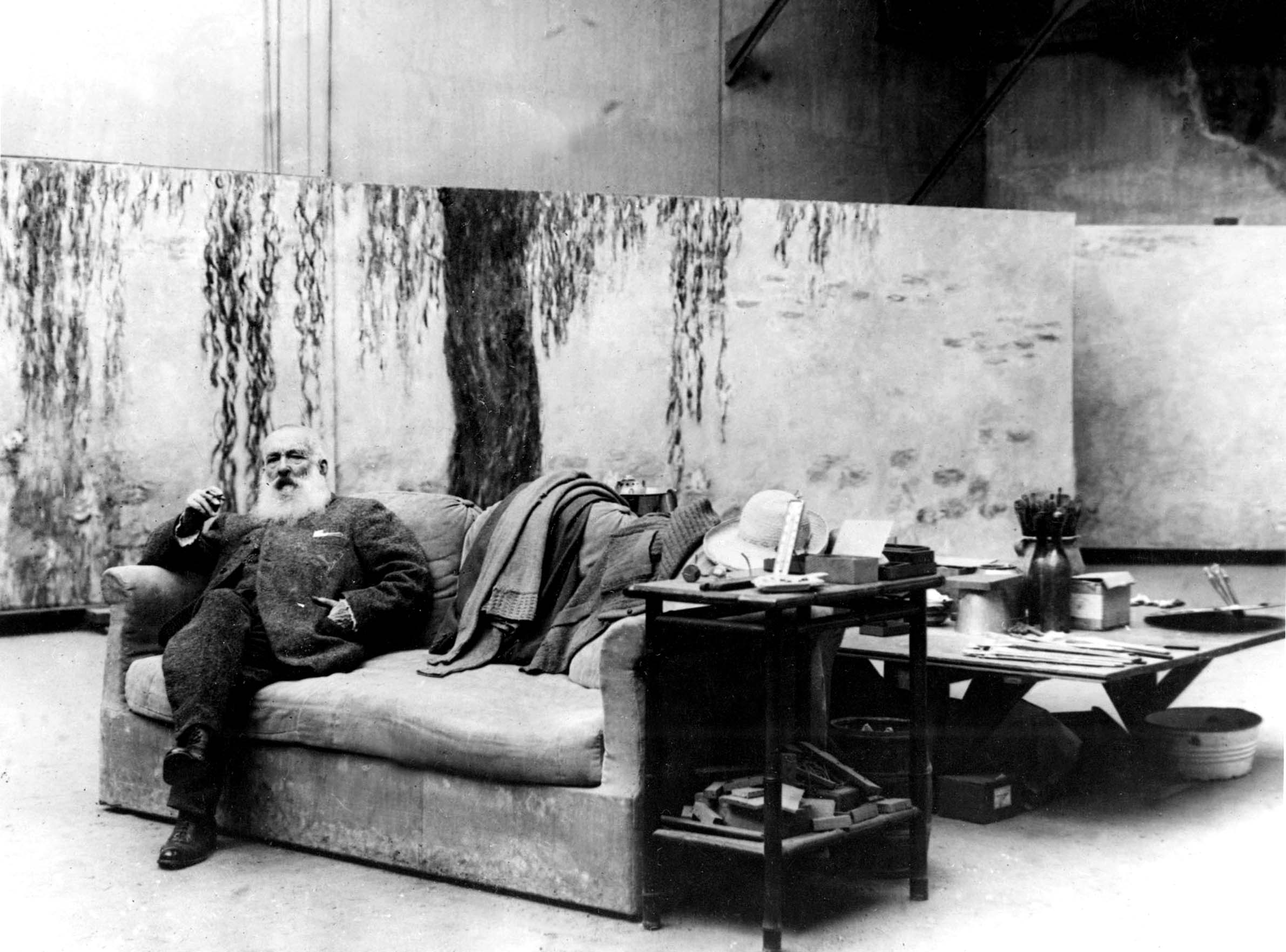 photo of the French painter Claude Monet in his workshop in front of one of his paintings Waterlilies c. 1918 / Bridgeman Images